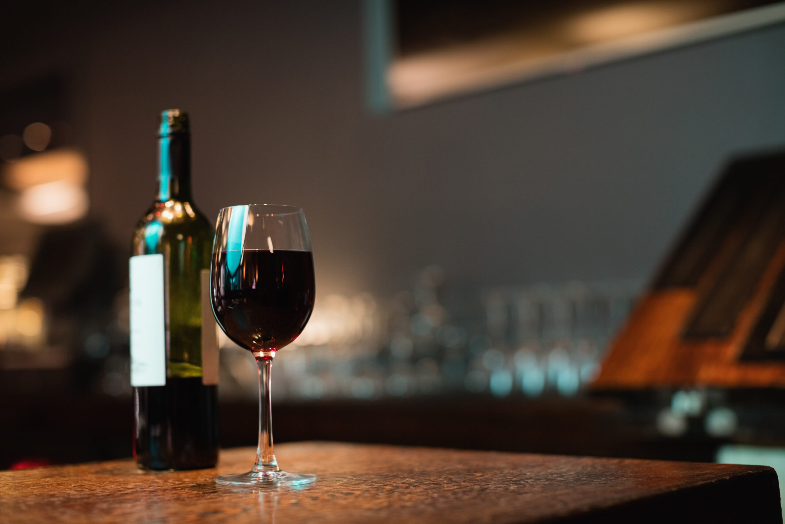 copa de vino tinto y botella en barra de bar scaled